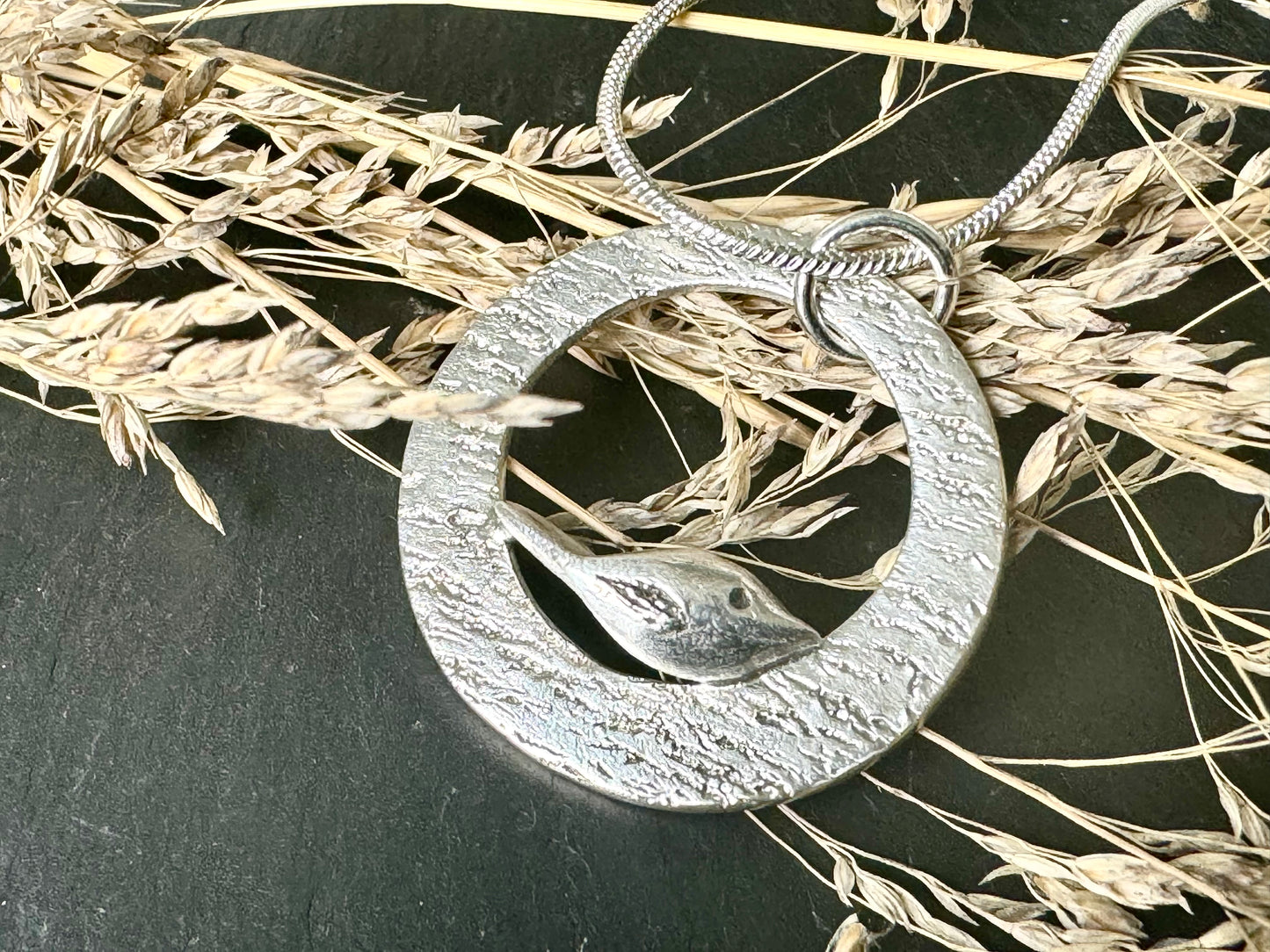 Handmade silver bird perching on silver rippled circle necklace