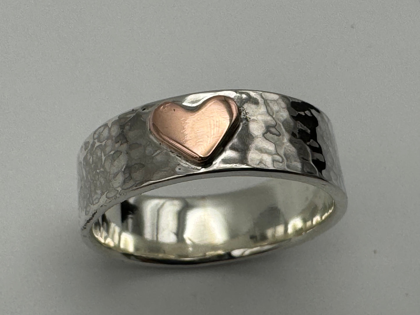 Handmade silver hammered band with a copper heart on the front.