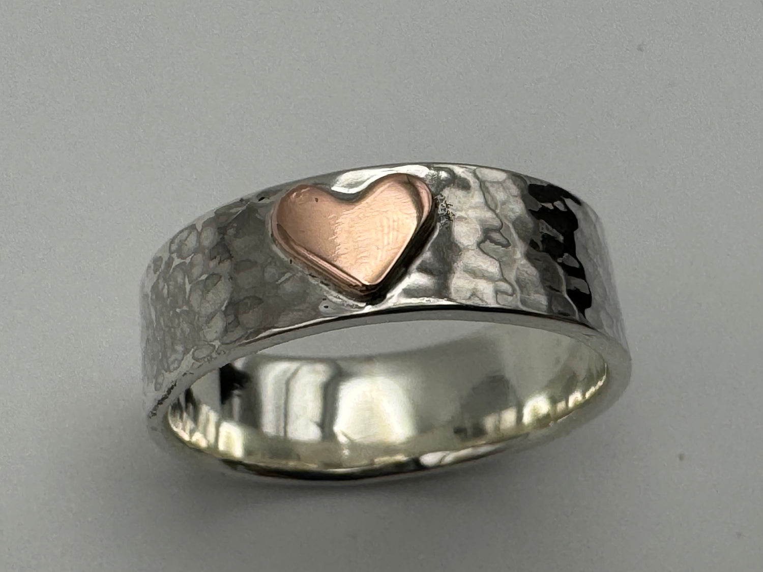 Handmade silver hammered band with a copper heart on the front.
