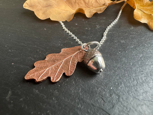 A copper oak leaf and silver acorn pendant on a silver chain 